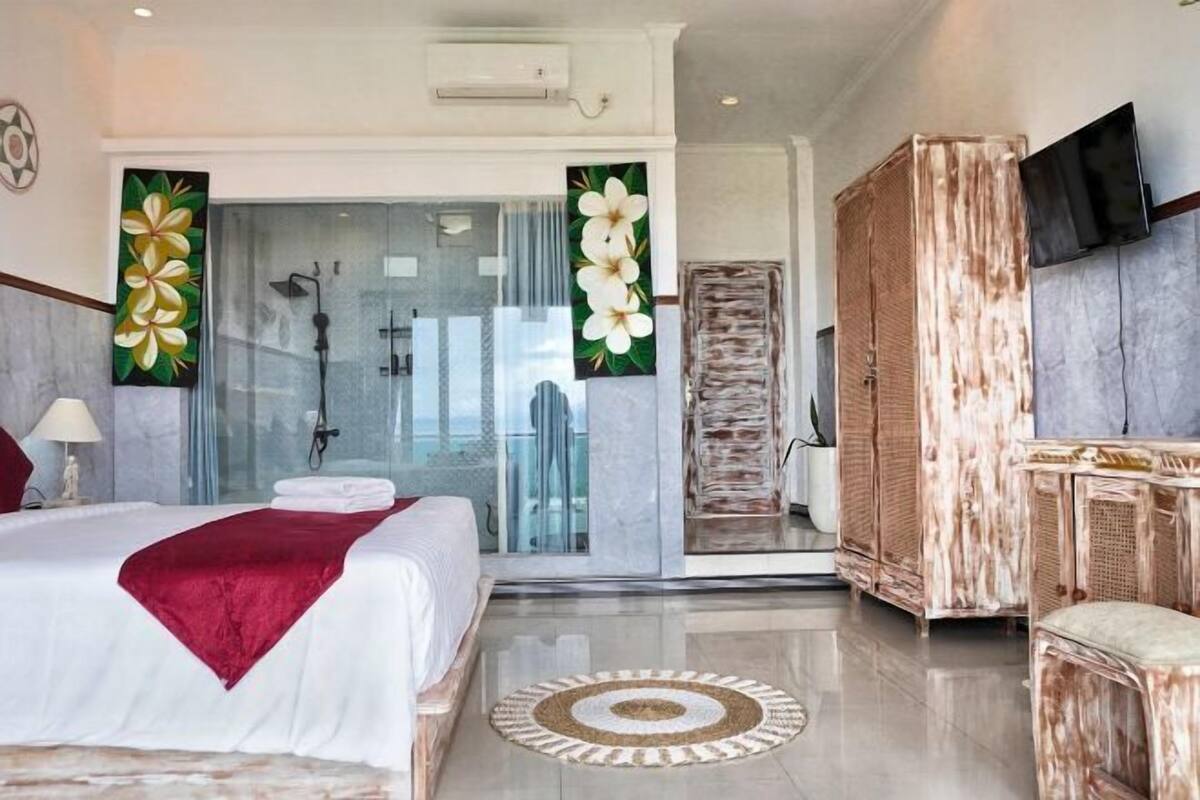 Una habitación de hotel moderna con una cama grande, ducha con cerramiento de vidrio, televisor y armario.