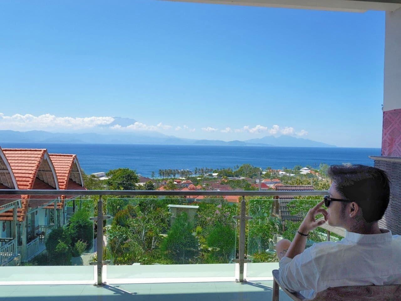 Un balcón con vista al océano y una zona residencial.