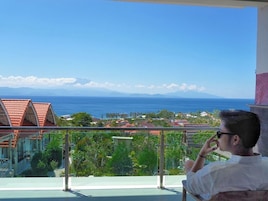 Un balcón con vista al océano y una zona residencial.