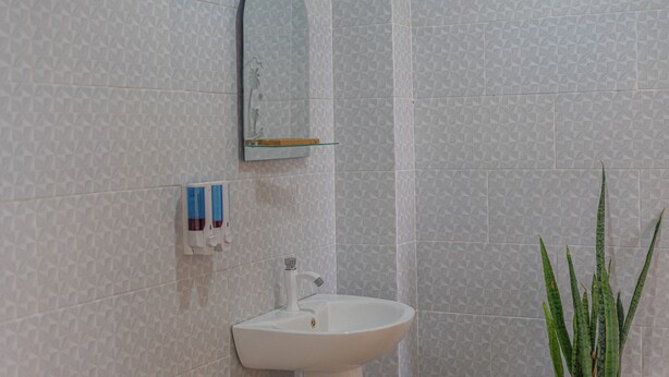 A bathroom with a white sink, a mirror, and a patterned wall. - Darya Sea View (Penida Island)