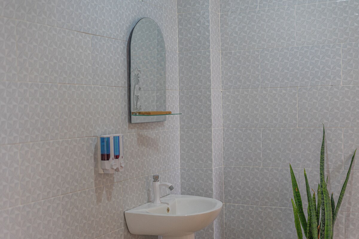 Een badkamer met een witte wastafel, een spiegel en een behang met een patroon.