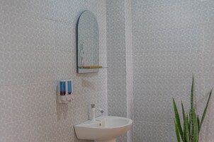 Un baño con un lavabo blanco, un espejo y un papel tapiz estampado.