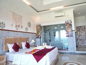 Ein geräumiges Schlafzimmer mit einem großen Bett, einer Glasdusche und Blick ins Bad.