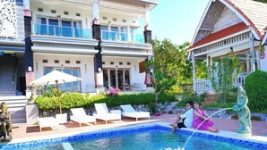 A swimming pool with lounge chairs, a statue, and a building with a balcony. - Darya Sea View (Penida Island)