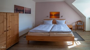 A bedroom with a wooden bed, two bedside tables, a chair, and a large window.