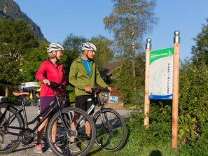Two people on bicycles near a signpost with a map. - Apartments Christiane (Oberammergau)