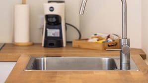 Et moderne køkken med en stålvask, kaffemaskine og en træbordplade.