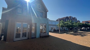 A building with large windows and a brick facade, a paved courtyard with benches, and a clear blue sky. - Unique House Within Walking Distance of the Beach (Katwijk Aan Zee)