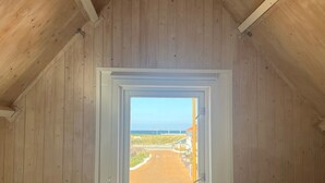 A wooden interior with a window revealing a beach view. - Unique House Within Walking Distance of the Beach (Katwijk Aan Zee)