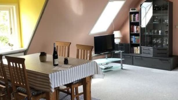 A dining area with a table and chairs, a television, and a bookshelf. - Holiday Apartment Hinrichsen 2 (Midlum)