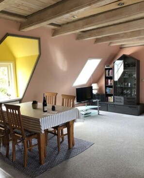 A dining area with a table and chairs, a television, and a bookshelf. - Holiday Apartment Hinrichsen 2 (Midlum)