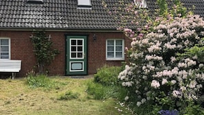 A brick house with a green door, two windows, and a small porch. - Holiday Apartment Hinrichsen 2 (Midlum)