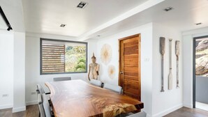A modern dining room with a large wooden table, a Buddha statue, and decorative wall art. - Serene Escape Villa in Chaweng - KBR20 (Koh Samui)