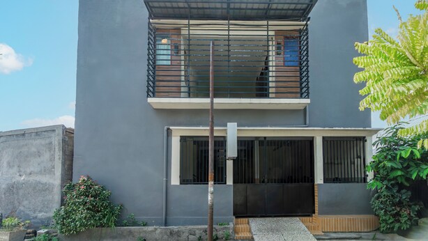 A modern two-story building with a flat roof, large windows, and a balcony.