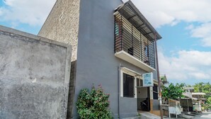 A modern building with a prominent pyramid-like structure, a balcony with metal railings, and a sign indicating a business or service.