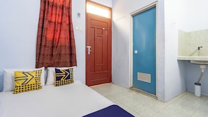 A hotel room with a bed, two pillows, a red door, a blue door, and a bathroom with a sink.
