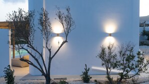 A modern building with a minimalist design, featuring a large white wall and two illuminated light fixtures. - Morphe Villa (Aspro Chorio)