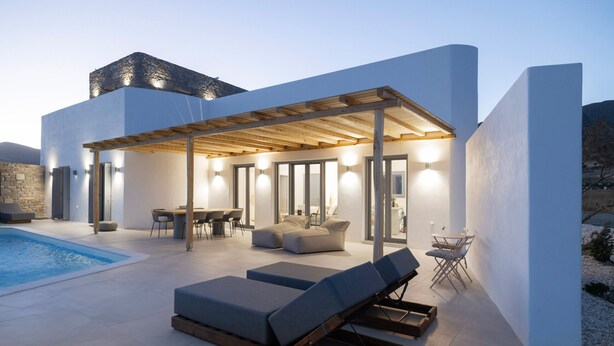 A modern outdoor living area with a pool, lounge chairs, and a covered patio. - Morphe Villa (Aspro Chorio)