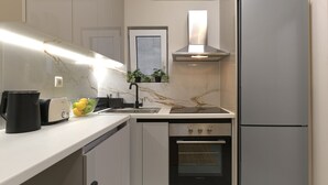 A modern kitchen with a built-in oven, a stainless steel refrigerator, and a black coffee maker on the counter.
