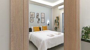 A bedroom with a bed, a wall-mounted air conditioner, and framed artwork.