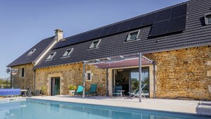 A stone building with a swimming pool, outdoor seating, and solar panels on the roof. - Christopha, holiday house with private pool (La Dornac)