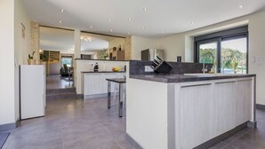 A modern kitchen with a central island, built-in appliances, and a view to the outdoors. - Christopha, holiday house with private pool (La Dornac)