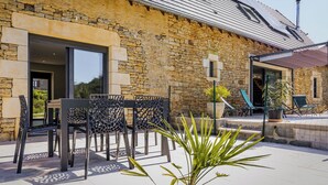 A stone building with a patio area featuring outdoor furniture and potted plants. - Christopha, holiday house with private pool (La Dornac)