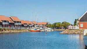 A marina with boats docked, a small island with a gazebo, and buildings with red roofs. - 4 Person Holiday Park Home in Borre (Borre)