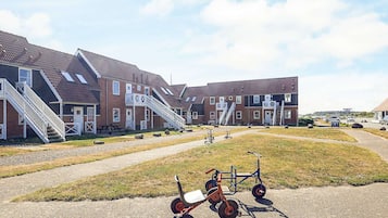 A row of brick buildings with external staircases and a gravel pathway in front.