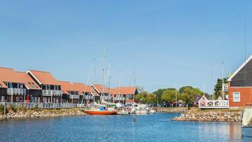 Uma marina com barcos atracados, uma pequena ilha com um gazebo e edifícios com telhados vermelhos.