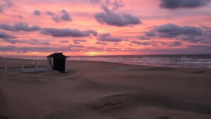 Una playa con una pequeña estructura, posiblemente un puesto de socorristas, y el océano.