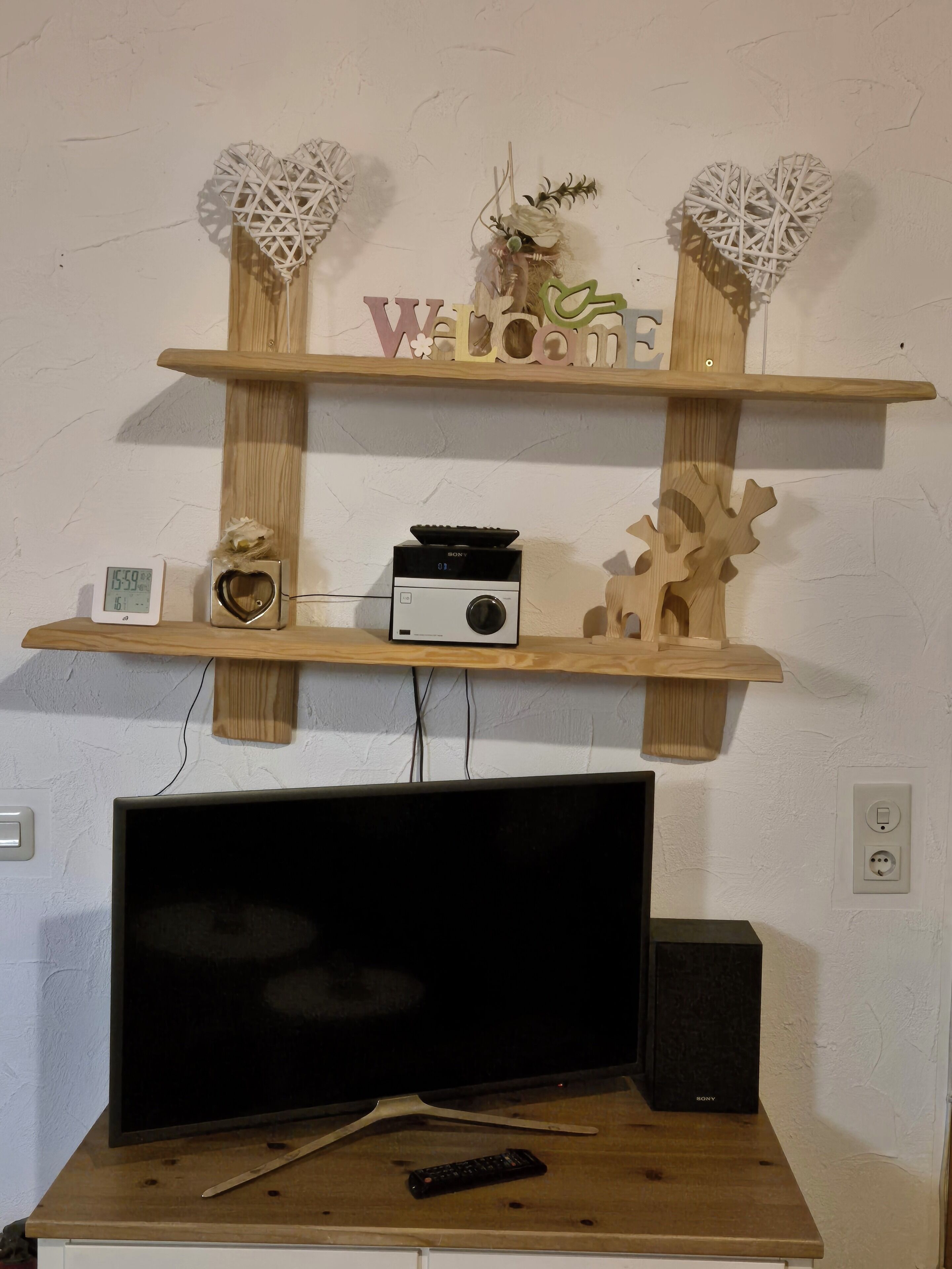 A wooden TV stand with a flat-screen TV, a Sony speaker, and a remote control.
