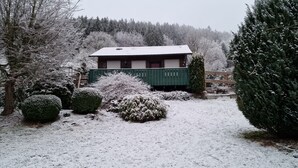 A house with a green fence, snow-covered bushes, and a snow-covered roof.