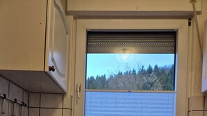 A kitchen with a window, a coffee maker, a microwave, and a knife block.