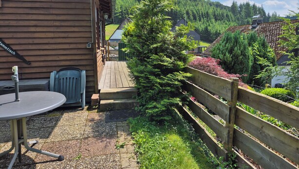 A wooden cabin with a patio area, a table, and chairs.