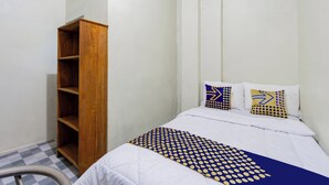 Ein kleines, ordentlich eingerichtetes Schlafzimmer mit einem Einzelbett, einem Holzschrank und einem Schachbrettfußboden.