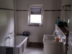 A bathroom with a bathtub, a sink, and a window.