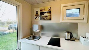 A compact kitchen with a sink, a kettle, a toaster, and a small window. - Lovely Holiday Home in Vlaanderen With Garden (De Haan)