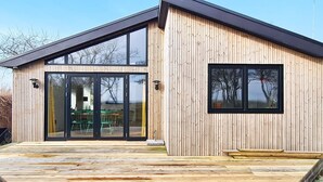 A modern wooden building with large sliding glass doors, a deck, and a small window. - 5 Star Holiday Home in Sydals (Sydals)