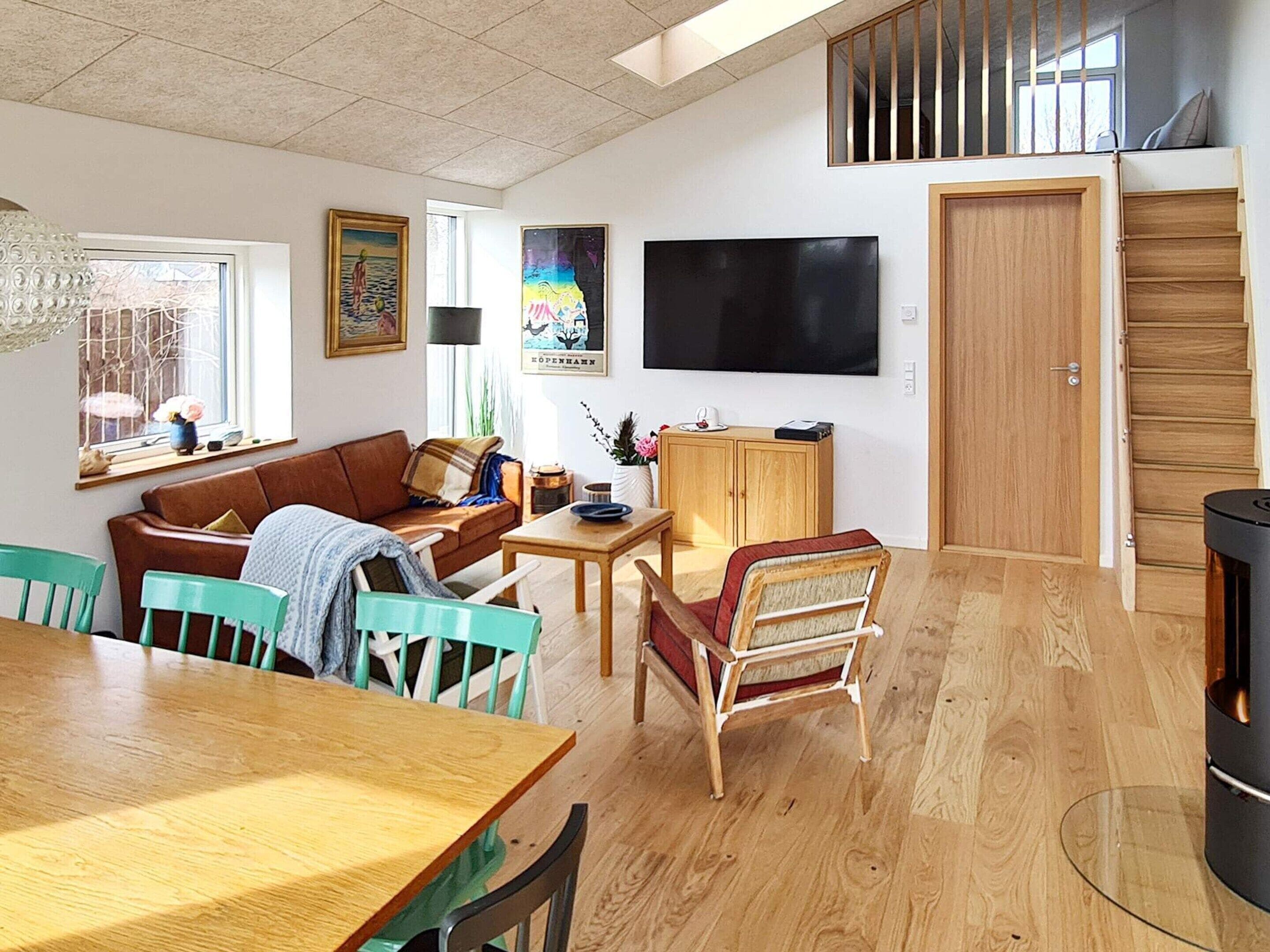 A living room with a sofa, chairs, a table, a TV, and a wooden door.