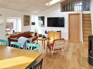 Un salon avec un canapé, des fauteuils, une table, un téléviseur et une porte en bois.