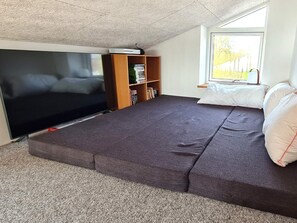 Une pièce comprenant un lit, un téléviseur, une bibliothèque et une fenêtre.