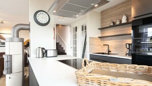 A modern kitchen with a central island, a stove, and a clock on the wall. - Reethuus Sud Modern Retreat (Juist)