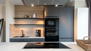 A modern kitchen with a built-in oven, a coffee machine, and a microwave. - Reethuus Sud Modern Retreat (Juist)