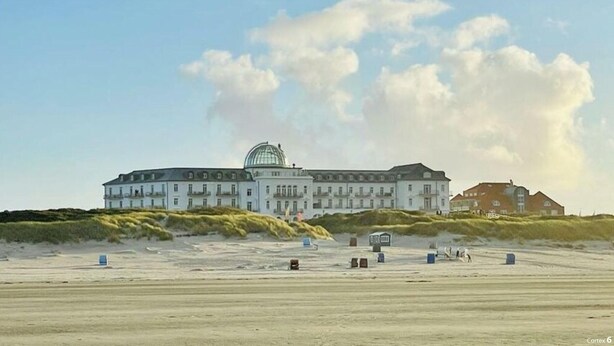 A large building with a dome on top, located on a sandy beach with dunes in the background. - Reethuus Sud Modern Retreat (Juist)