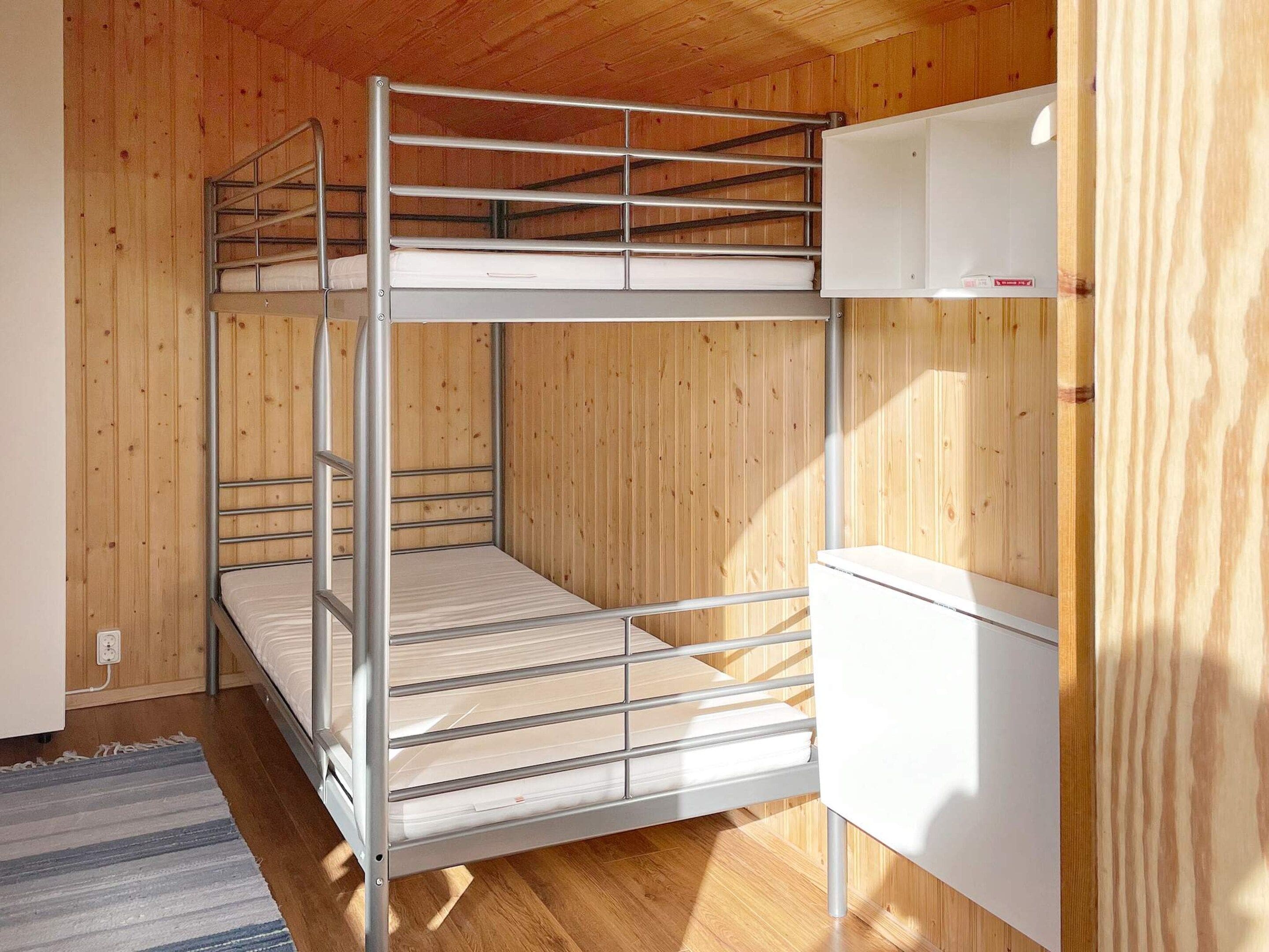 Uma cama de beliche com cabeceira branca e um pequeno armário branco em cima.