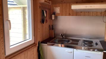 Una cocina compacta con ventana, paredes de madera, un lavamanos, una estufa y un lavavajillas.