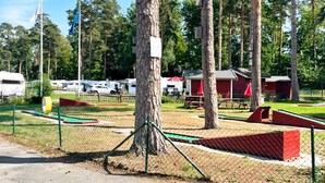A fenced outdoor area with picnic tables and a red building.