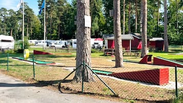 Un espacio al aire libre con mesas de picnic y un edificio rojo, delimitado por una cerca.