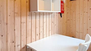 A room with a white table and a white chair, a white cabinet, and a red fire safety sign on the wall.